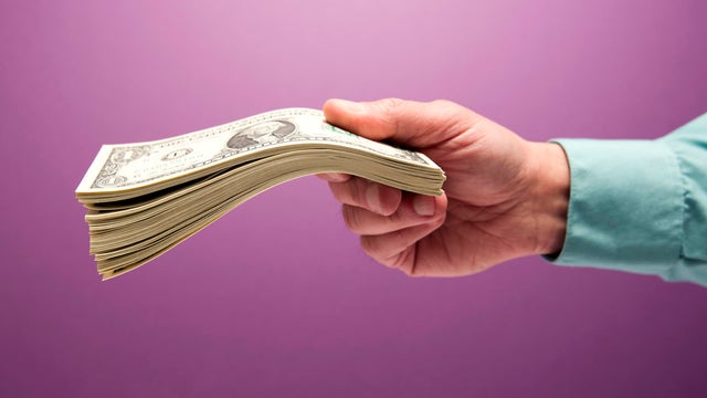 Man's hand holding stack of cash 